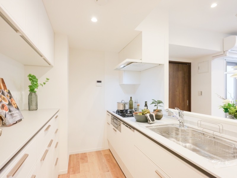 お部屋のインテリアのように溶け込むホワイト基調の明るいオープンキッチンです。レンジフードまでお色を揃えたキッチンスペースには、豊富な収納、カウンター部分がゆったりとしたカップボードが備わっています。
