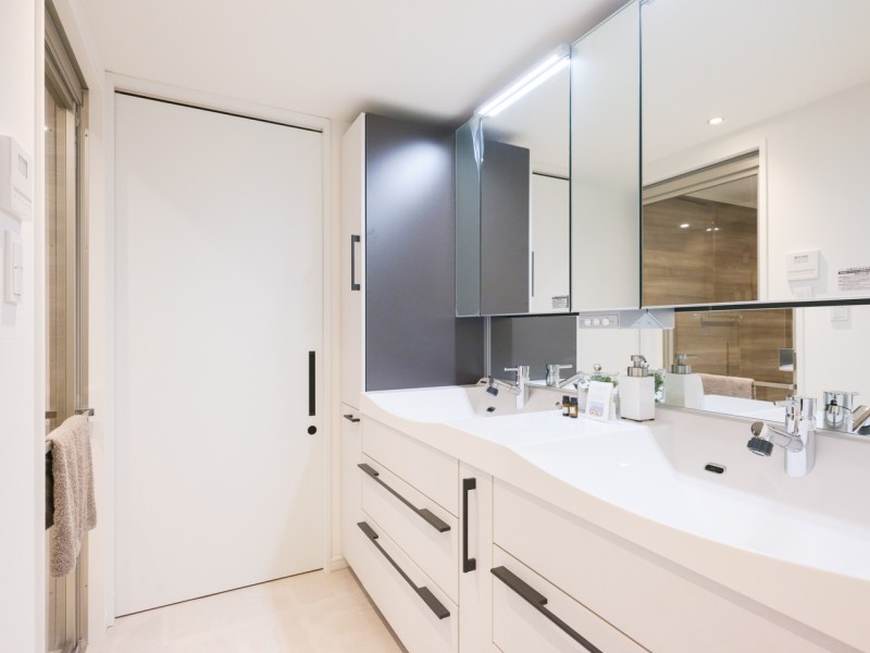 ゆとりある洗面スペースです。ダブルボウルの大きな洗面台は大きな鏡で身だしなみも整えやすく、朝の慌ただしい時間帯も快適です。洗面台横には収納棚もございますので、リネン類などの収納にも便利です。