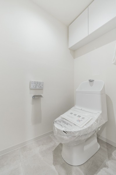 TOTO製ウォシュレット一体型のトイレは、お掃除の手助けをしてくれる便利機能が搭載されています。背面には収納に便利な吊戸棚収納を備え付けているので、床にものを置かず、すっきりと使えるレストルームです。