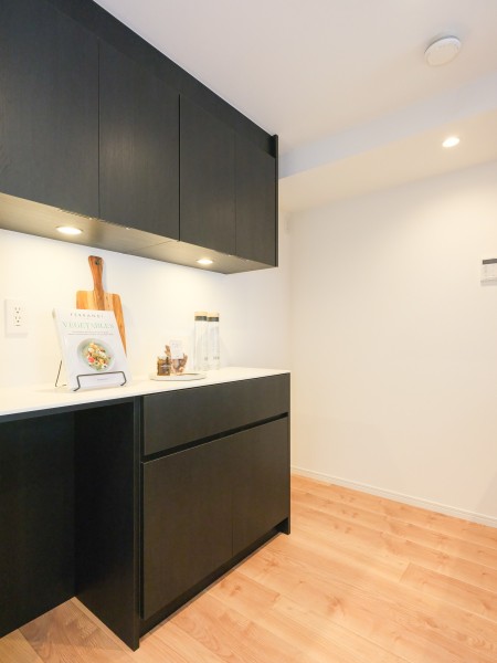キッチン背面にはお揃いのカップボードがあり、作業スペースとしても便利です。間接照明が優しく照らし、より洗練された空間へと演出します。