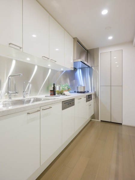 白を基調とした壁付けタイプのシステムキッチンは、空間を明るく清潔感のある印象に演出します。収納力に優れ、デザイン性と機能性を兼ね備えた使い勝手のよいキッチンです。
