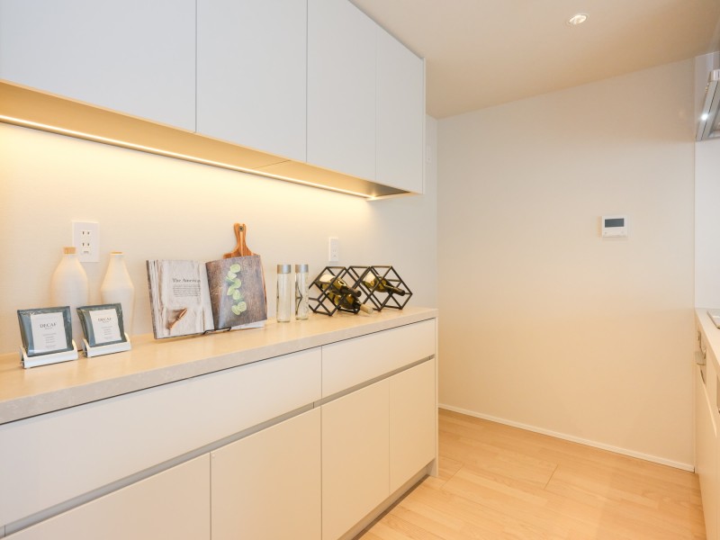 キッチン背面にはお揃いのカップボードを設置。間接照明が照らすカウンターはゆとりがあり、キッチン家電を配置しやすいスペースです。