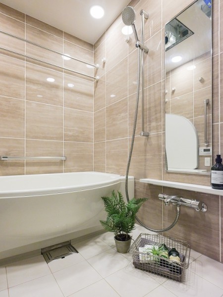 光沢のあるデザインパネルが配されたラグジュアリーなバスルーム。背の高いミラーは空間をより広く感じさせ、大きなシャワーヘッドを構えるシャワーバーはスライド式で使い勝手の良い設備です。