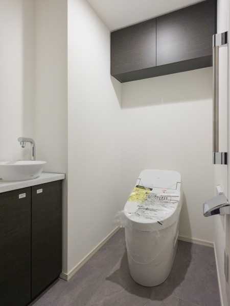 上品さが宿るレストルームには空間をすっきりと保つことが叶う上部吊戸棚収納、スマートなタンクレストイレが設置されています。手洗いカウンター付きでゲストの皆様も動線を気にすることなくお使いいただけます。