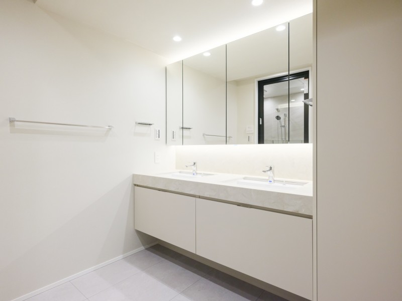 大きな鏡が印象的なラグジュアリーな洗面室です。キッチンと同じ田中工藝製のオリジナル洗面化粧台を採用しました。ホテルライクな2ボウルの洗面化粧台も見どころです。